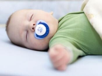 תינוק ישן על גבו עם מוצץ בפיו