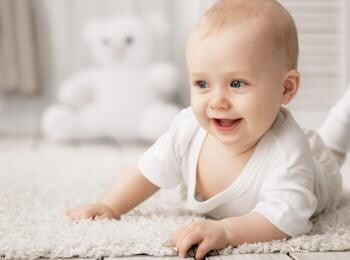 תינוק שמח כבן חצי שנה, שוכב על ביטנו