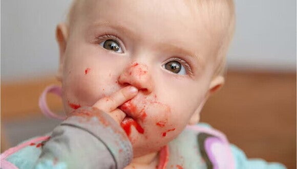 תינוק מכניס יד לפה עם אוכל תינוקות