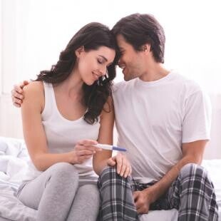 זוג מחובק מתבונן בבדיקת הריון