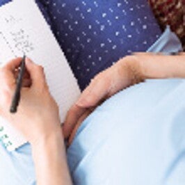 אישה הרה כותבת רשימה - תצלום מלמעלה